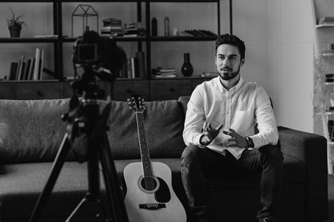 music blogger sitting on sofa and talking about acoustic guitar